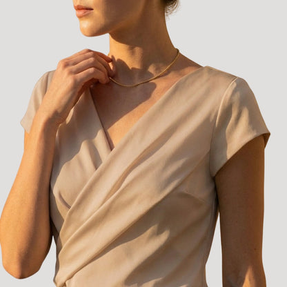 Women's draped wrap-front blouse in white and khaki with a V-neckline, back view